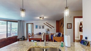 Eine Küche mit Granit-Arbeitsplatte, Edelstahlspüle und Pendelleuchten.