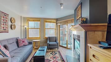 A living room with a sofa, armchair, small round table, and a patterned rug.