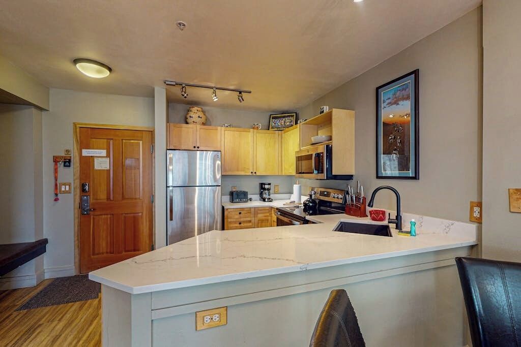 A compact kitchen with a central island, built-in appliances, and a wooden door.