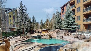 A pool area with hot tubs, lounge chairs, and a view of surrounding buildings. - Ski-In/Out Condo with Shared Pool, Hot Tub & Sauna - Walk to Village (Keystone)