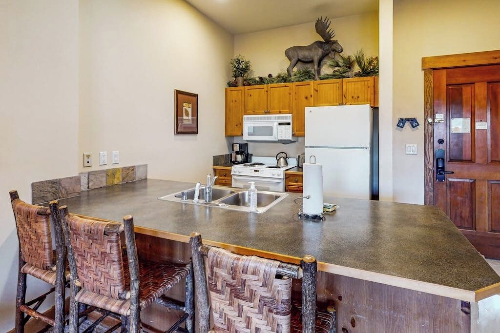 Una cocina con una isla central, armarios de madera, un microondas, un refrigerador y un alce decorativo.