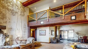 A spacious lobby with a high ceiling, a wooden staircase, and a stone fireplace. - Ski-In/Out Condo with Shared Pool, Hot Tub & Sauna - Walk to Village (Keystone)