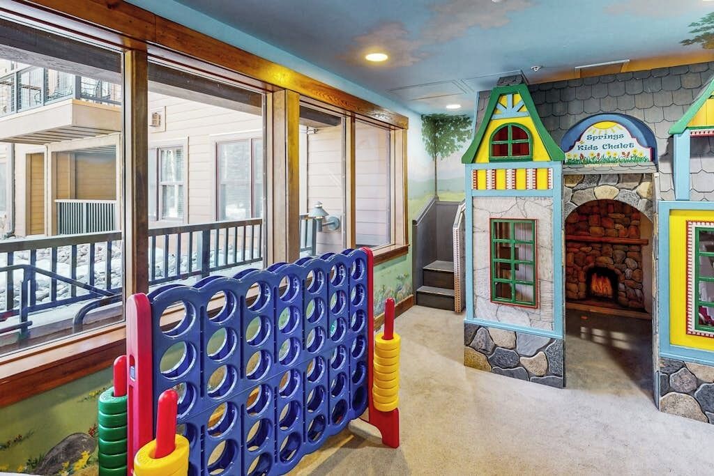 A children's play area with a playhouse, a stone fireplace, and a view of the outside.