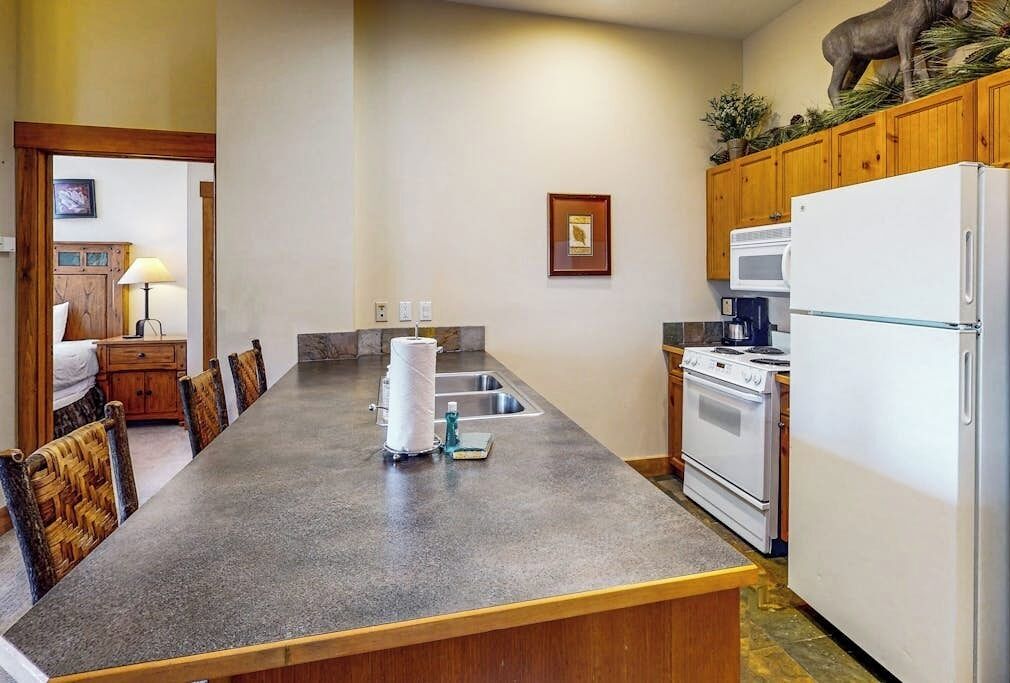 A kitchen with a central island, wooden cabinets, a refrigerator, and a stove.