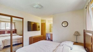 Una camera da letto con un grande specchio, un letto, una cassettiera, una sveglia e una lampada.