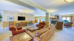 A spacious living room with a fireplace, comfortable seating, and a television. - Cozy condo with shared hot tub & private deck- close to the slopes (Keystone)