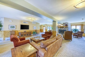 A spacious living room with a fireplace, comfortable seating, and a television. - Cozy condo with shared hot tub & private deck- close to the slopes (Keystone)