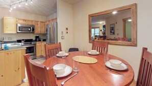 A dining area with a wooden table, chairs, and a large mirror on the wall. - Cozy condo with shared hot tub & private deck- close to the slopes (Keystone)