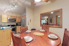 A dining area with a wooden table, chairs, and a large mirror on the wall. - Cozy condo with shared hot tub & private deck- close to the slopes (Keystone)