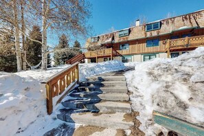 A wooden staircase leading to a building with a balcony, surrounded by snow and trees. - Studio with updated interior, fireplace & W/D - Vail Village bus access (Vail)