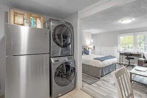 A compact room with a bed, a desk, a chair, a washing machine, and a refrigerator. - Studio with updated interior, fireplace & W/D - Vail Village bus access (Vail)