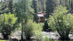 A lodge surrounded by dense forest, with a visible building structure and a river in the background. - 2nd-floor chalet with fireplace, grill, balcony, washer/dryer, ski & mtn views (Vail)