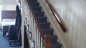 Eine Treppe mit Holzbalken, einer weißen Wand und einem Deckenventilator.