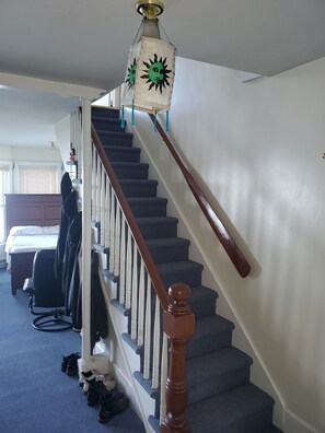 Eine Treppe mit Holzbalken, einer weißen Wand und einem Deckenventilator.