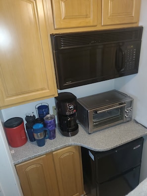 Eine kleine Küche mit einer Mikrowelle, einem Toaster und einer Kaffeemaschine auf der Arbeitsfläche.