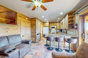 A modern kitchen with wooden cabinetry, a central island with bar stools, and a ceiling fan.