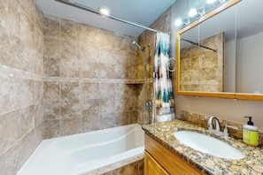 A bathroom with a bathtub, a shower, a sink, and a mirror.