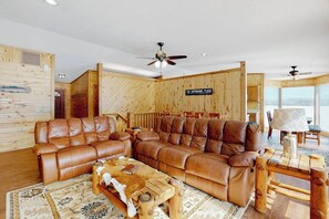 Ein Holzinterieur mit einem großen, braunen Leder-Sectional und einem Holztisch sowie einem Deckenventilator.