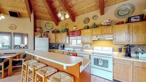 Una cocina con armarios de madera, una isla central con taburetes de bar, una estufa y un microondas.