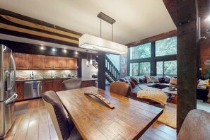 Eine moderne Küche mit Holzausstattung, einem Esstisch und einer Treppe, die zu einem Schlafbereich führt.