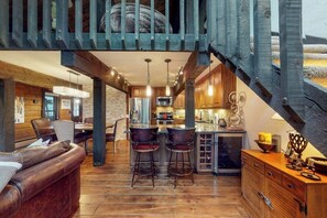 Eine rustikale Küche mit Holzschnitzschränken, einer Bar mit Hockern und einer Treppe.
