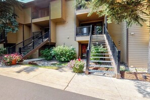A multi-story building with a central staircase, balconies, and a small garden area with flowers. - Large, inviting home with fabulous valley views, hot tubs & grills (Steamboat Springs)