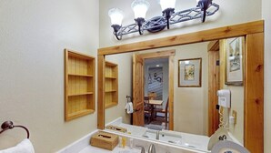 Ein Badezimmer mit großem Spiegel, Waschbecken, Toilette und Duschbereich.