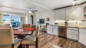 A modern kitchen with white cabinets, a dining area with a red placemat, and a view of the outdoors. - Lovely Lakefront Condo with  Fireplace, Free High-Speed WiFi and Stunning Views (Dillon)