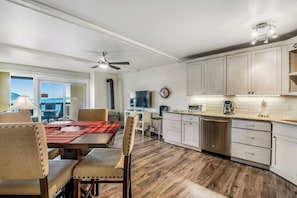 A modern kitchen with white cabinets, a dining area with a red placemat, and a view of the outdoors. - Lovely Lakefront Condo with  Fireplace, Free High-Speed WiFi and Stunning Views (Dillon)