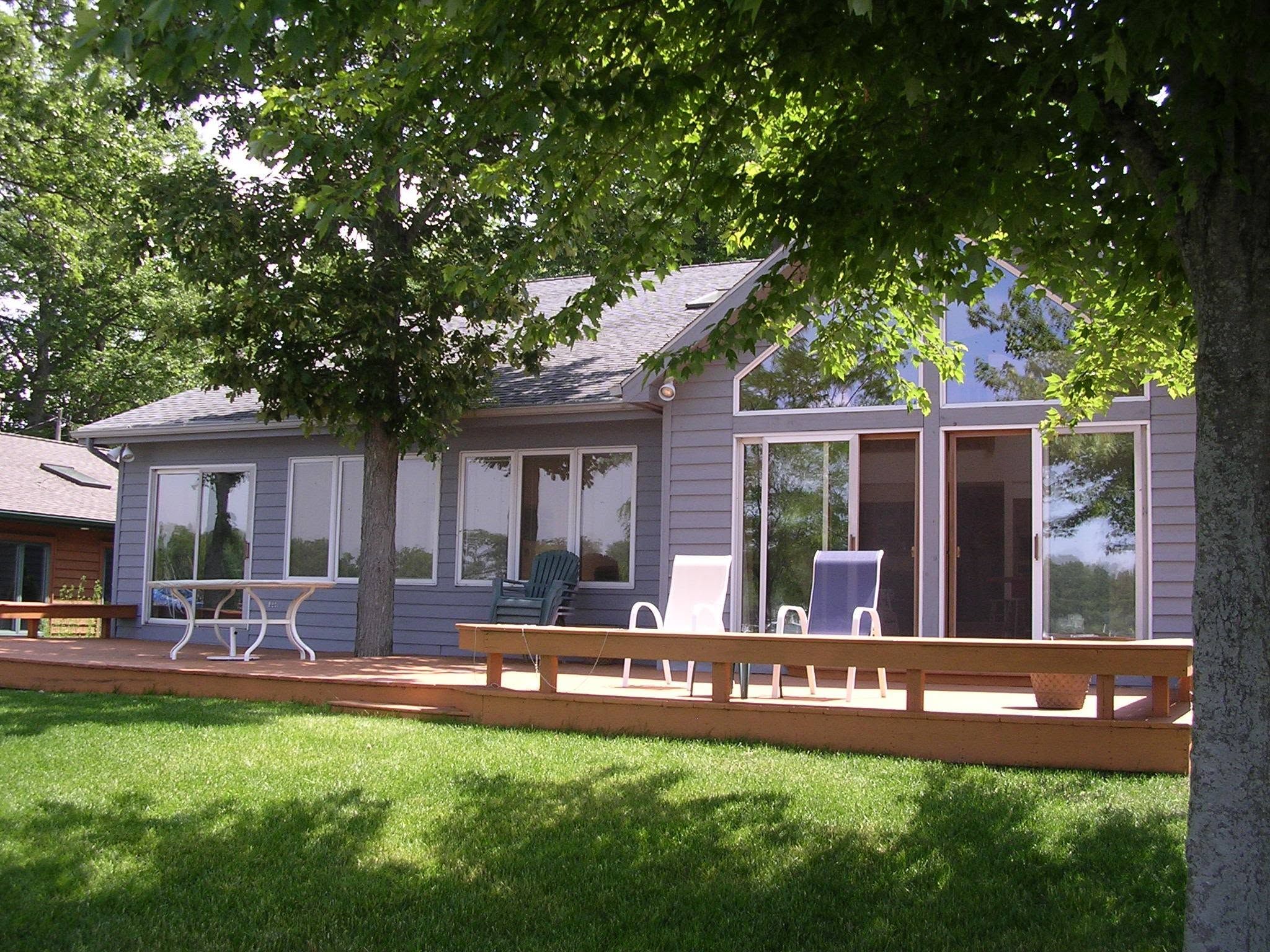 A house with a covered porch, outdoor seating, and a large window overlooking a grassy area.