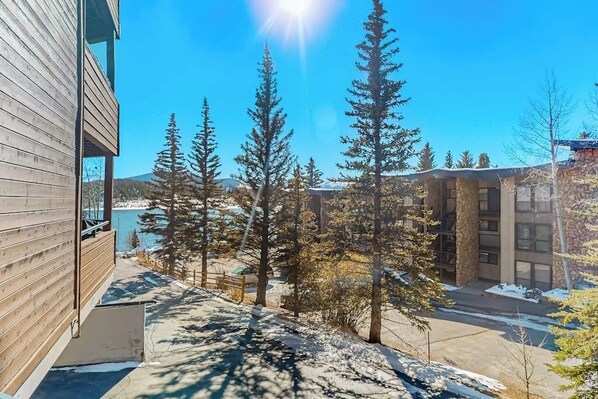 A building with a wooden exterior, a view of a lake, and surrounding trees. - Waterfront condo with full kitchen & wifi - convenient location (Dillon)