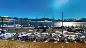 Ein Yachthafen mit angestuften Booten, bewölkter Himmel und einem Bergpanorama im Hintergrund.