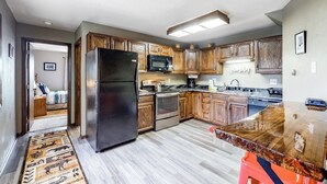 Una cocina con armarios de madera, un refrigerador de acero inoxidable, un microondas y una encimera de granito.