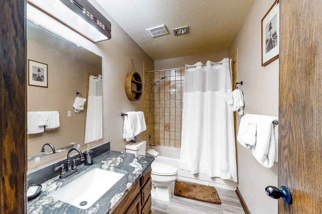A bathroom with a sink, toilet, shower, and a mirror.