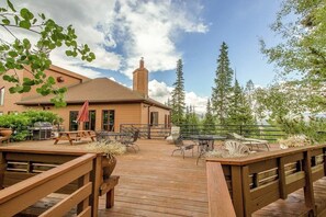 Eine Holterrasse mit Sitzgelegenheit, einem Grill und einem Gebäude mit Schornstein.