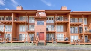 Un edificio de apartamentos de madera de varios pisos, con balcones, una entrada central y una pequeña ventana en la planta baja.