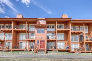 Ein mehrgeschossiges Holzwohnhaus mit Balkonen, einem zentralen Eingang und einem kleinen Fenster im Erdgeschoss.