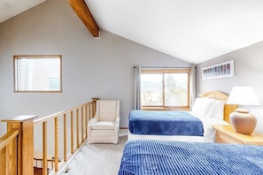 Ein Schlafzimmer mit zwei Betten, einem Sessel, einer Holzreling und einem Fenster.