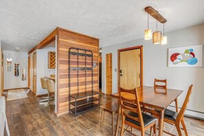 Ein Essbereich mit Holztisch und Stühlen, einem Metallregal und einem Holzschrank.