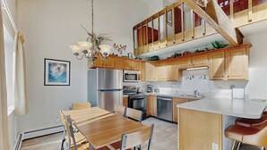 Eine moderne Küche mit Holzausstattung, einer zentralen Kochinsel und einem Essbereich mit Holztisch und Stühlen.
