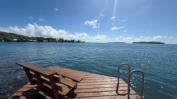 A wooden pier extending into calm waters with a bench and metal handrails.