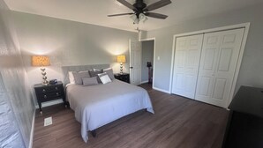 Quarto com cama, mesas de cabeceira, ventilador de teto e guarda-roupa.