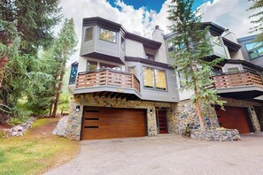 A modern multi-story house with a stone facade, large garage doors, and a balcony. - Spacious Family Friendly Townhome, Grill, near Golf, and Bus Stop (Vail)