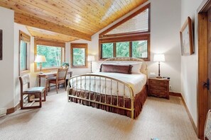 A bedroom with a wooden ceiling, a bed with a metal frame, two bedside tables, and a chair. - Spacious Family Friendly Townhome, Grill, near Golf, and Bus Stop (Vail)