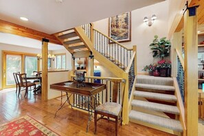 A wooden staircase with a carpeted landing, a dining area with a table and chairs, and a large window. - Spacious Family Friendly Townhome, Grill, near Golf, and Bus Stop (Vail)