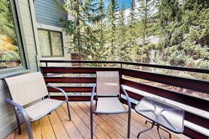 A balcony with two chairs and a table, surrounded by a wooden deck and a view of trees. - Spacious Family Friendly Townhome, Grill, near Golf, and Bus Stop (Vail)
