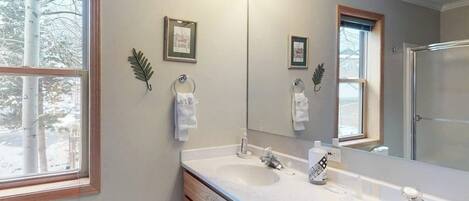 Un baño con dos lavamanos, un espejo grande y una ventana.