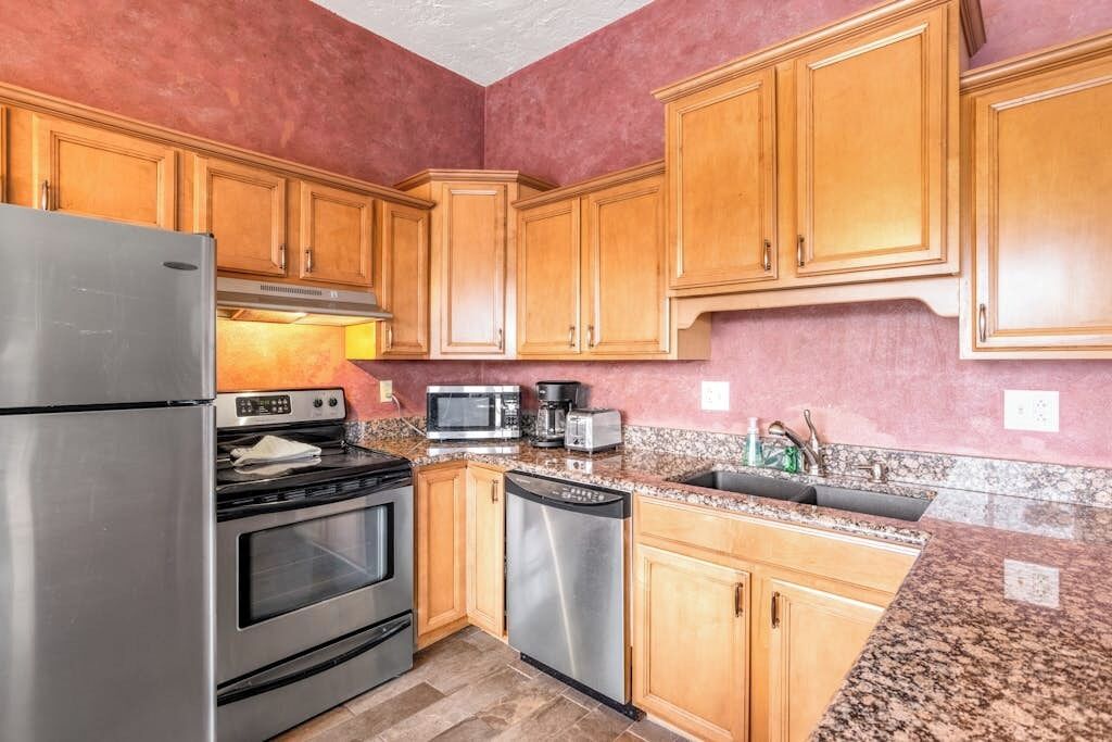 A kitchen with wooden cabinets, stainless steel appliances, and granite countertops.