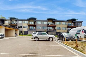 A multi-story residential building with balconies, a parking lot, and a white van parked in front. - Cozy condo w/ full kitchen, fast wifi, balcony & convenient location (Silverthorne)