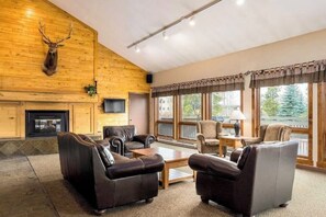 A log cabin interior with leather sofas, a fireplace, and large windows. - Updated condo with pool, hot tubs & washer/dryer - steps from Steamboat lift (Steamboat Springs)